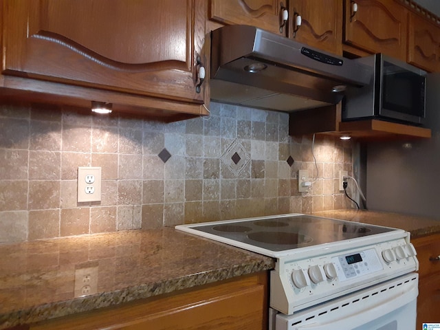 kitchen with decorative backsplash, dark stone counters, and white electric stove