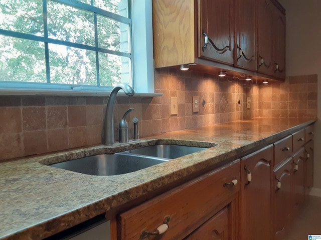 kitchen featuring backsplash, sink, a wealth of natural light, and light stone counters