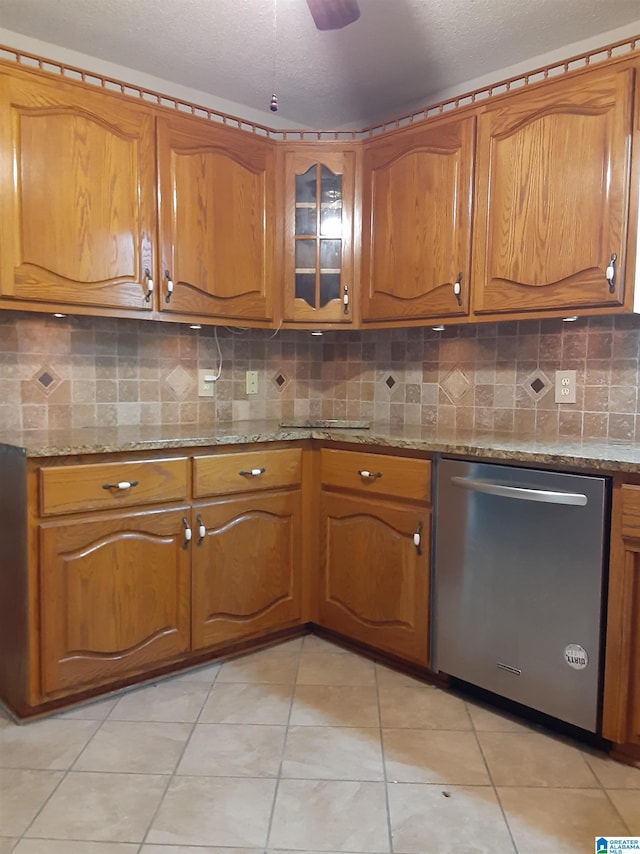 kitchen with light tile patterned flooring, light stone countertops, tasteful backsplash, and stainless steel dishwasher