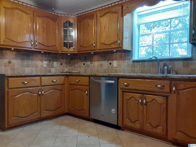 kitchen with light stone counters, decorative backsplash, stainless steel dishwasher, and light tile patterned floors