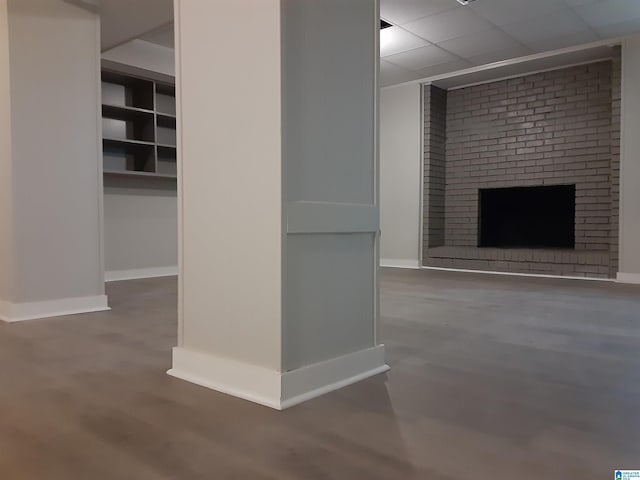 unfurnished living room featuring a paneled ceiling and a brick fireplace