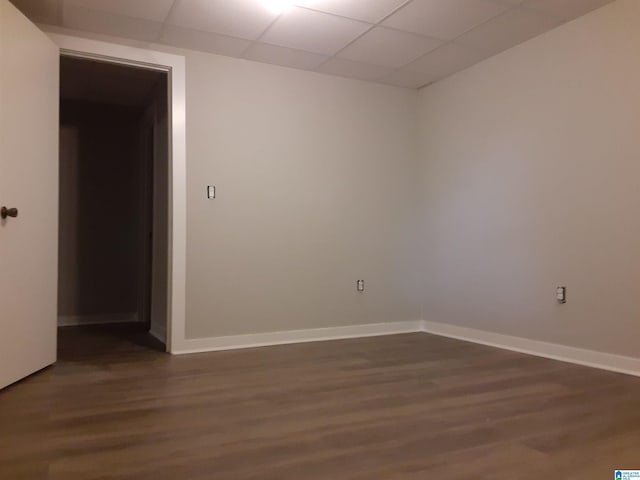 unfurnished room featuring dark wood-type flooring and a paneled ceiling