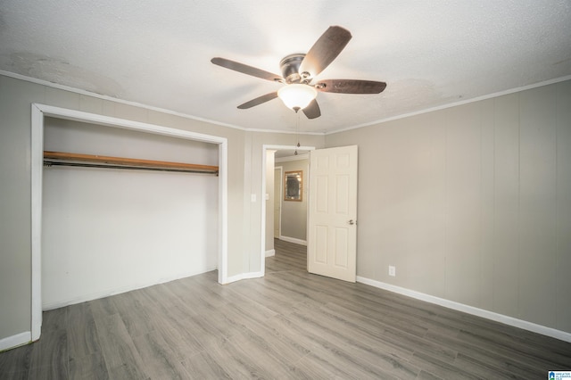 unfurnished bedroom featuring crown molding, hardwood / wood-style floors, ceiling fan, and a closet