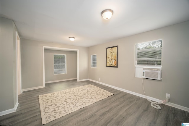 spare room with a healthy amount of sunlight, cooling unit, and dark wood-type flooring