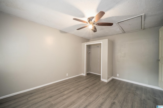 empty room with a textured ceiling, ceiling fan, and dark hardwood / wood-style flooring