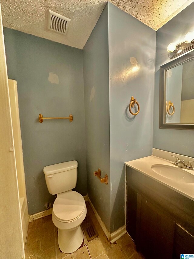 bathroom with tile patterned floors, a textured ceiling, vanity, and toilet