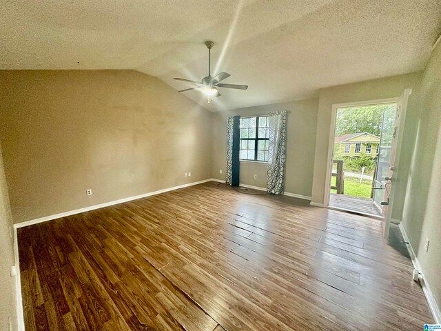 empty room featuring ceiling fan, a textured ceiling, lofted ceiling, and hardwood / wood-style floors