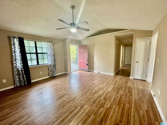 empty room featuring lofted ceiling, ceiling fan, hardwood / wood-style flooring, and a textured ceiling