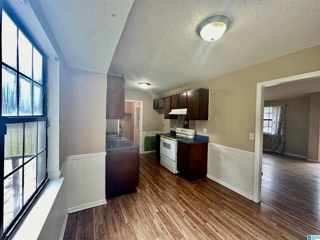 kitchen with a textured ceiling, dark brown cabinetry, white range with electric cooktop, and wood-type flooring