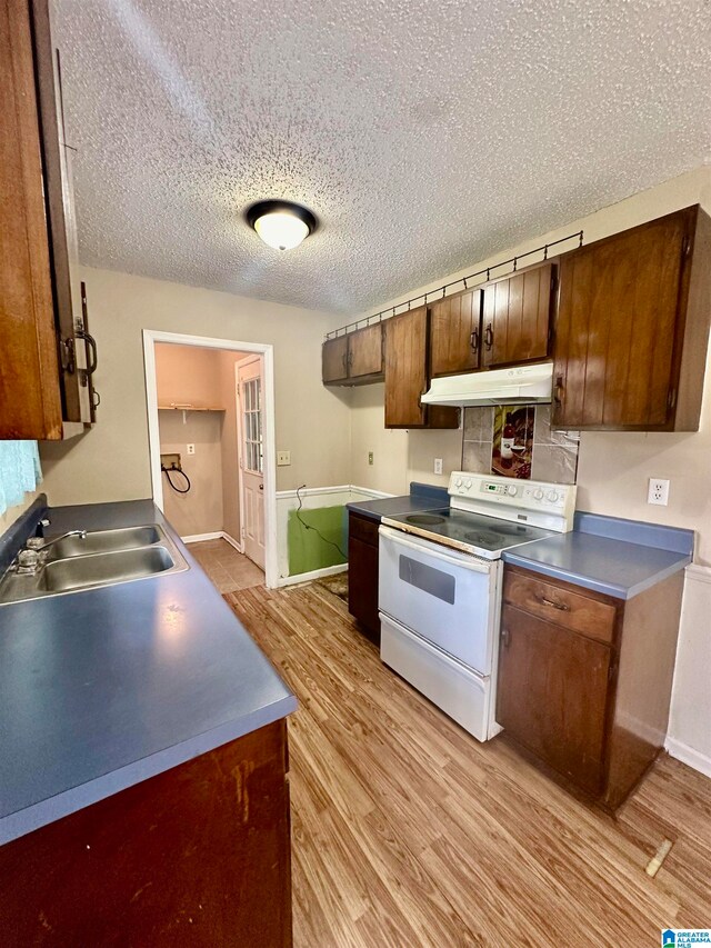 kitchen featuring white range with electric cooktop, a textured ceiling, light hardwood / wood-style flooring, and sink