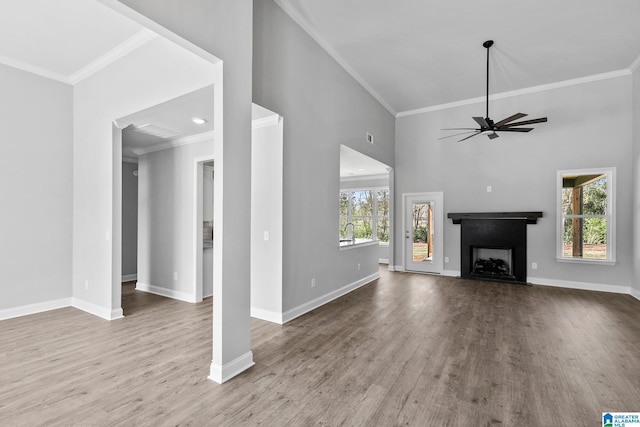 unfurnished living room with baseboards, wood finished floors, ornamental molding, and ceiling fan