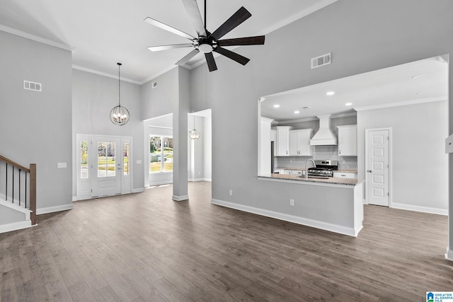 unfurnished living room with high vaulted ceiling, a sink, ornamental molding, and visible vents