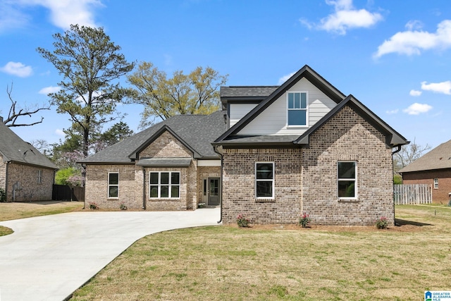 craftsman-style home featuring a shingled roof, a front yard, fence, brick siding, and driveway