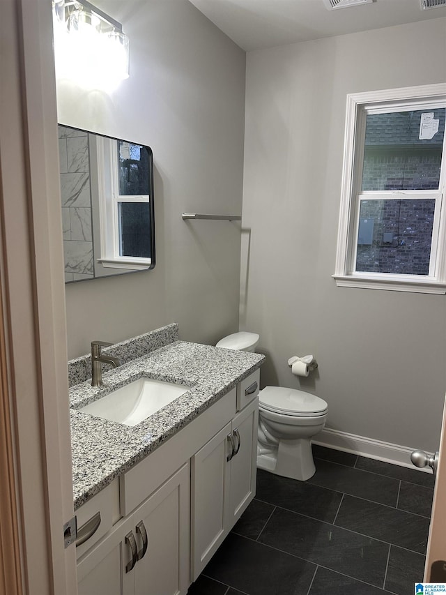 bathroom with toilet, vanity, and tile patterned floors