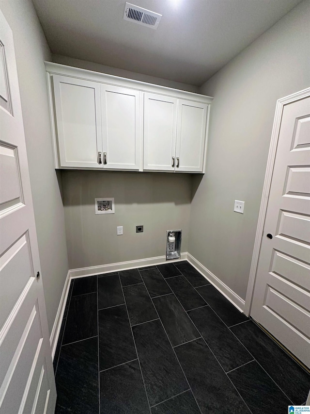 laundry area with dark tile patterned flooring, cabinets, and hookup for a washing machine