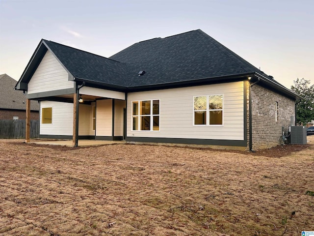 back house at dusk featuring central AC unit and a patio area