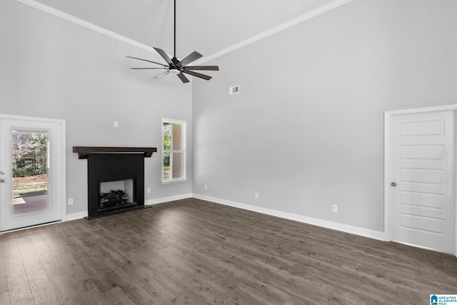 unfurnished living room with dark wood finished floors, baseboards, a towering ceiling, and a healthy amount of sunlight
