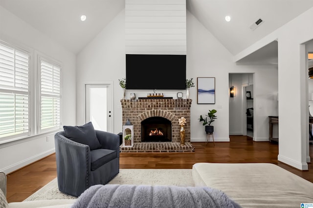 living room with a brick fireplace, hardwood / wood-style floors, and high vaulted ceiling