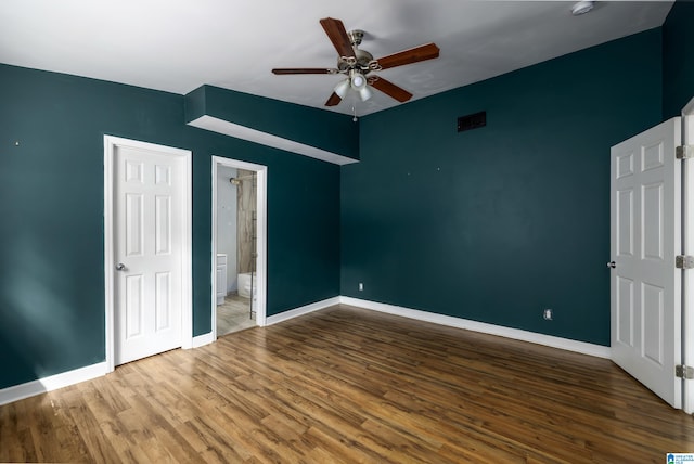 unfurnished bedroom with connected bathroom, ceiling fan, and hardwood / wood-style floors