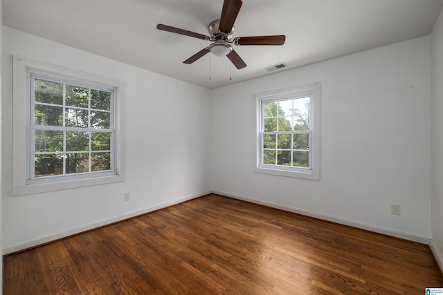 empty room featuring dark wood-type flooring, ceiling fan, and a healthy amount of sunlight