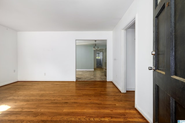 spare room featuring wood-type flooring and a chandelier