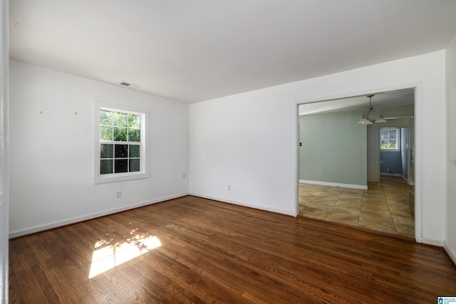 empty room with dark hardwood / wood-style floors and a notable chandelier