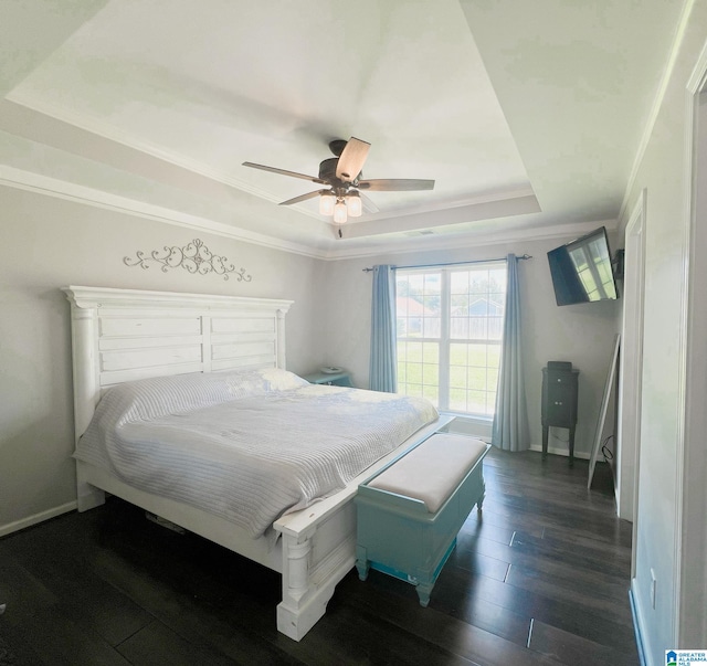 bedroom featuring ornamental molding, a tray ceiling, ceiling fan, and dark wood-type flooring