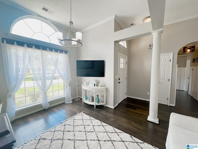 entrance foyer with a healthy amount of sunlight, crown molding, dark hardwood / wood-style floors, and ornate columns