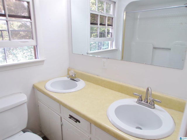 bathroom with walk in shower, vanity, and toilet