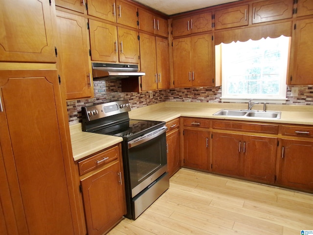 kitchen featuring decorative backsplash, light wood-type flooring, electric stove, and sink