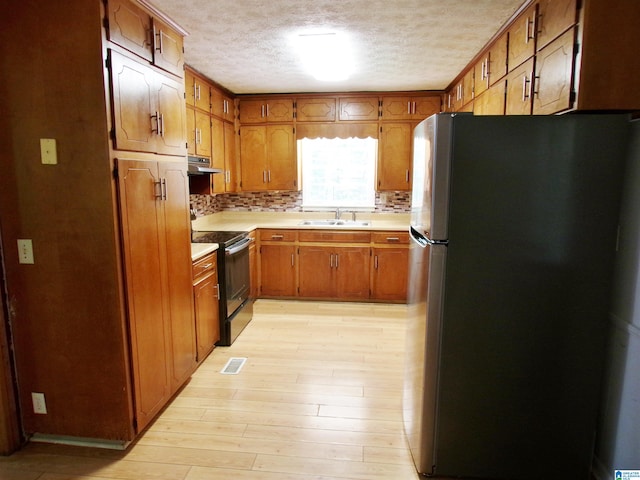 kitchen featuring light hardwood / wood-style floors, stainless steel refrigerator, range hood, black electric range oven, and sink