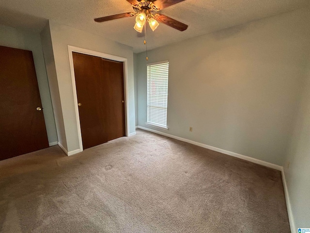 unfurnished bedroom with ceiling fan, carpet floors, a closet, and a textured ceiling