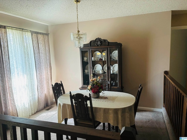 carpeted dining room featuring an inviting chandelier and a textured ceiling