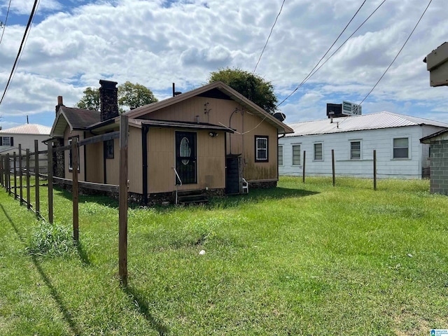 rear view of house featuring central AC unit and a yard