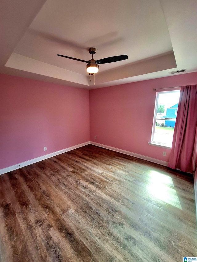 unfurnished room featuring wood-type flooring, a raised ceiling, and ceiling fan