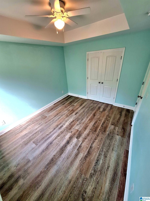 unfurnished bedroom with dark wood-type flooring, ceiling fan, and a closet