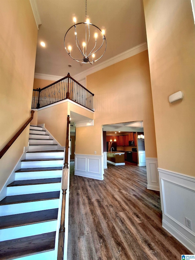 stairs featuring wood-type flooring, crown molding, and a high ceiling