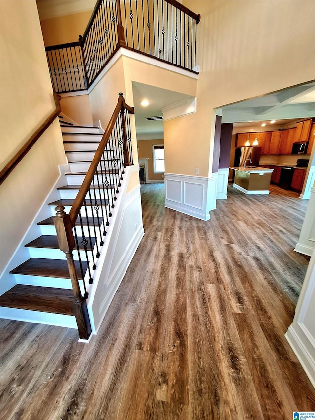 staircase featuring a towering ceiling and hardwood / wood-style flooring