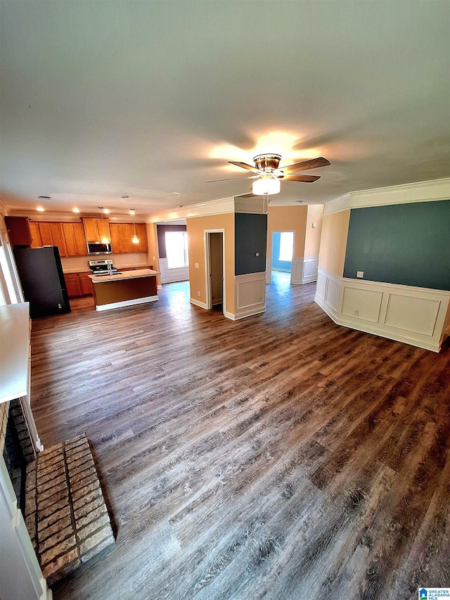 unfurnished living room with ornamental molding, dark hardwood / wood-style flooring, and ceiling fan