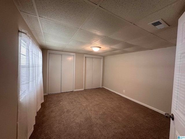 carpeted spare room featuring a drop ceiling