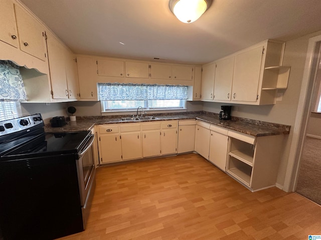 kitchen with light wood-type flooring, black range with electric cooktop, sink, and plenty of natural light