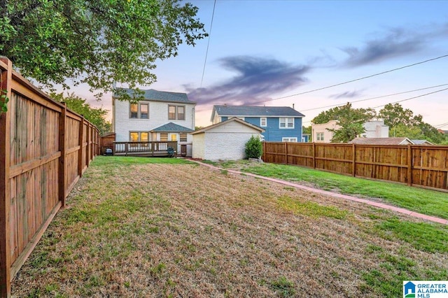 back house at dusk featuring a yard and a wooden deck