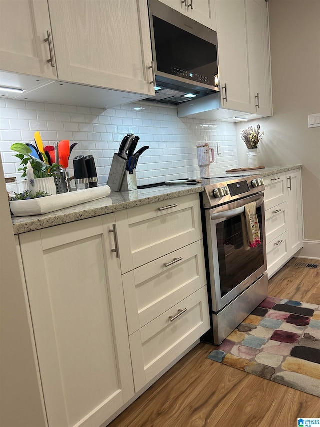 kitchen with light stone countertops, stainless steel appliances, dark hardwood / wood-style floors, and tasteful backsplash