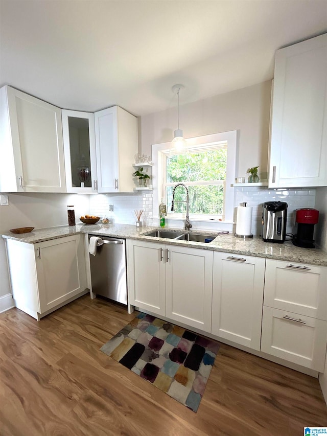 kitchen featuring hanging light fixtures, white cabinetry, dark wood-type flooring, stainless steel dishwasher, and sink