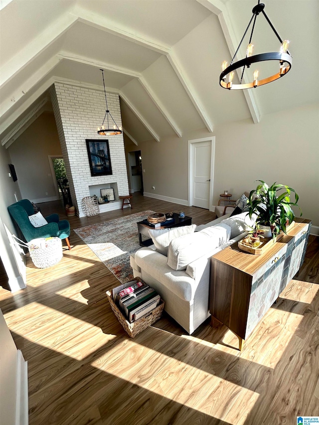 living room with vaulted ceiling, a chandelier, a brick fireplace, and hardwood / wood-style flooring