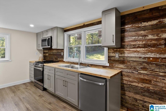 kitchen featuring light hardwood / wood-style floors, gray cabinets, sink, stainless steel appliances, and backsplash