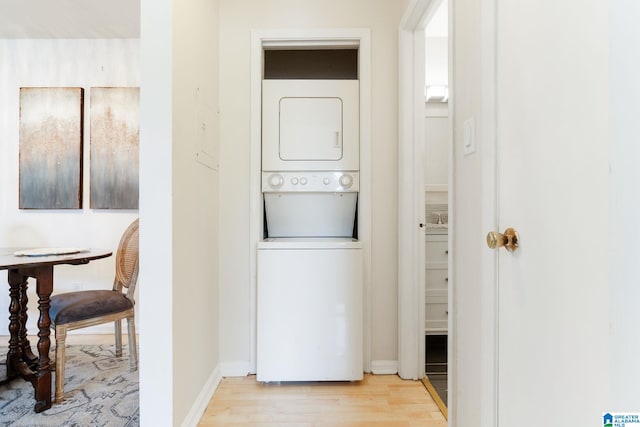 laundry room with stacked washer / dryer and light hardwood / wood-style floors