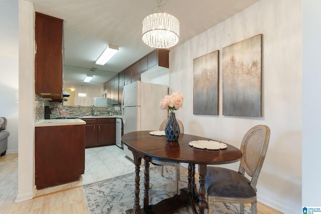 dining area with light wood-type flooring, a chandelier, and sink