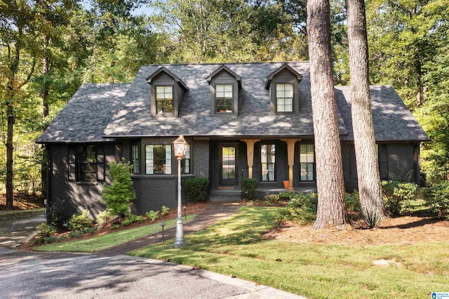 new england style home with covered porch and a front yard