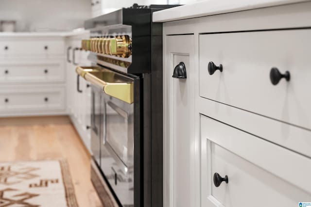 interior space with stainless steel range oven, light hardwood / wood-style floors, and white cabinetry